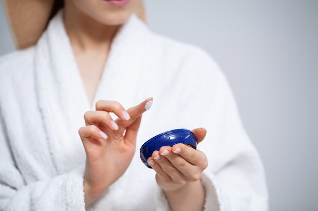 Close up woman puts a cream for face on hand