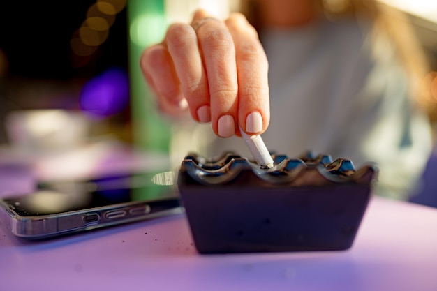 Close up of a woman putting finished cigarette in an ashtray