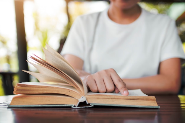 Chiuda sulla donna che legge il vecchio libro novello in caffè