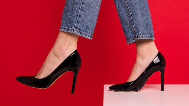 Primo piano dei piedi di una donna in scarpe nere su sfondo rosso