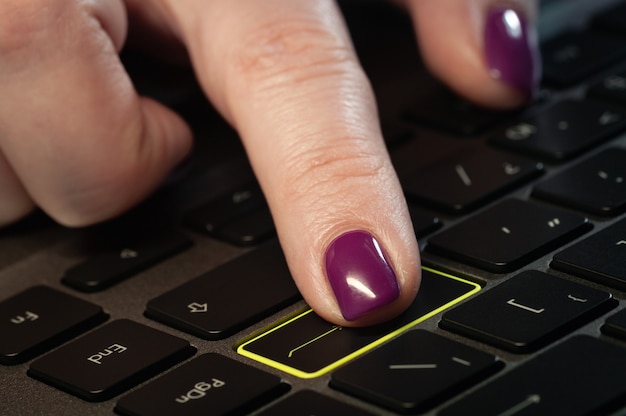 Close up woman's finger pressing enter button on the laptop keyboard.