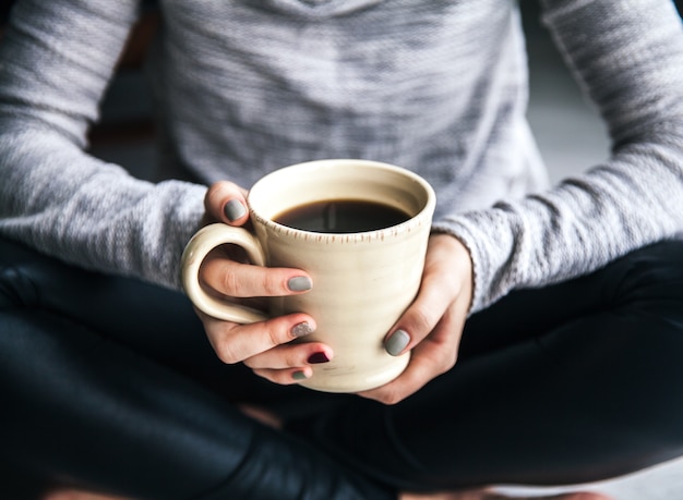 ホットコーヒーのカップを持っている女性の手のクローズアップ。ファッション、レジャー