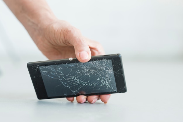 Foto primo piano della mano della donna che tiene smartphone con schermo rotto