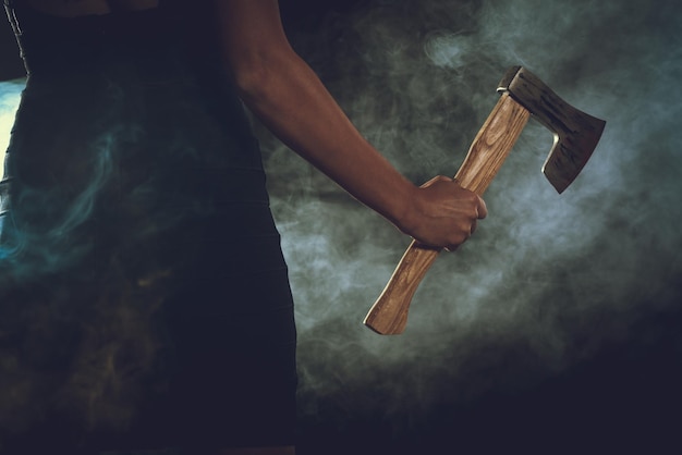 Close-up of a woman's hand with a axe in a smoky dark space