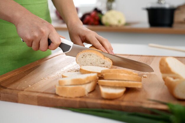 Close up of woman's hands cooking in the kitchen. Housewife slicing white bread. Vegetarian and healthily cooking concept.