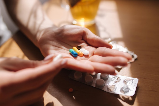 Close up of woman's hands hold pills Hand with pills and black tea with lemon Immunity Vitamines