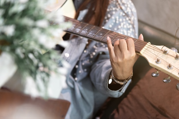 Chiuda sulle mani della donna che giocano la chitarra acustica.