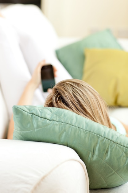 Close-up of a woman sending a text lying on a sofa