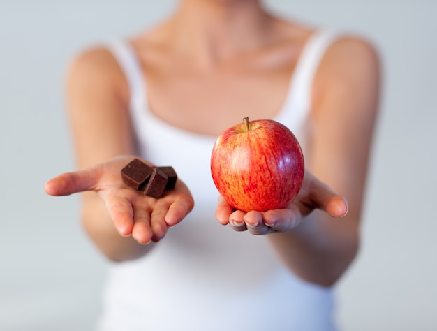 Close up of woman showing chocolate and apple focus on apple 