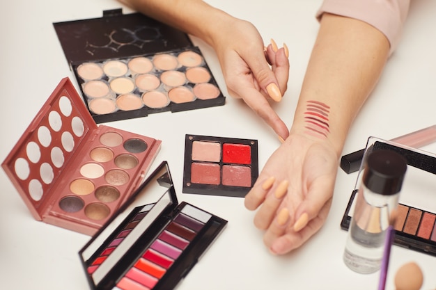 Close-up of woman showing different colors of eyeshadows on her hand and consulting about the decorative cosmetics