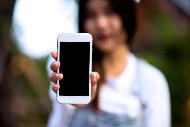 Foto close-up di una donna che mostra un telefono cellulare all'aperto