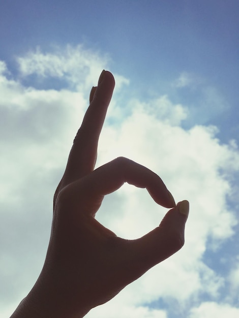 Photo close-up of woman showing ok sign against sky