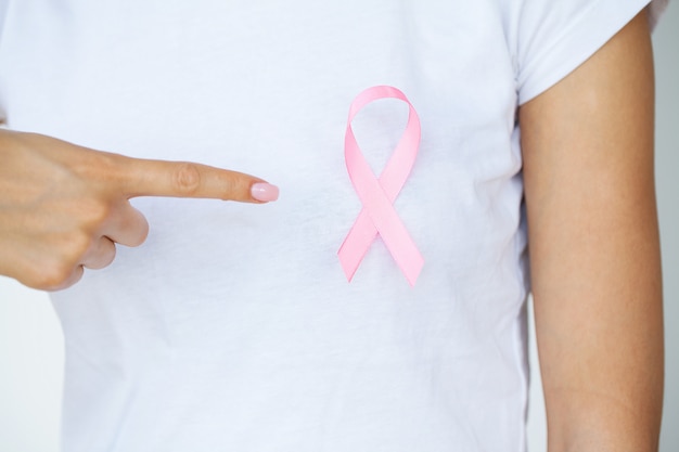 Close up of woman showing pink ribbon symbolizing breast cancer