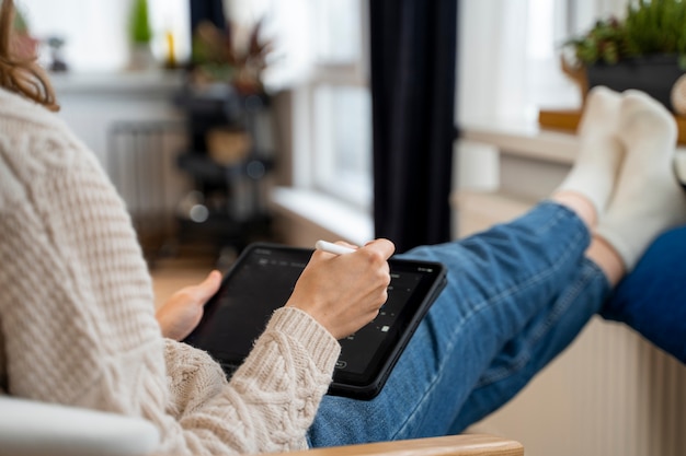 Close up woman sitting near heater with tablet