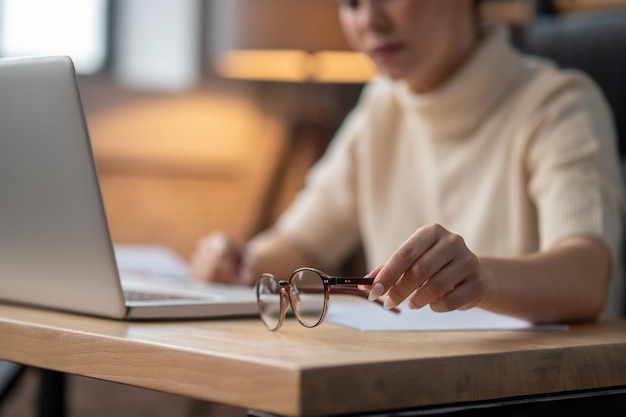 A close up of a woman sitting at the table and working on laptop