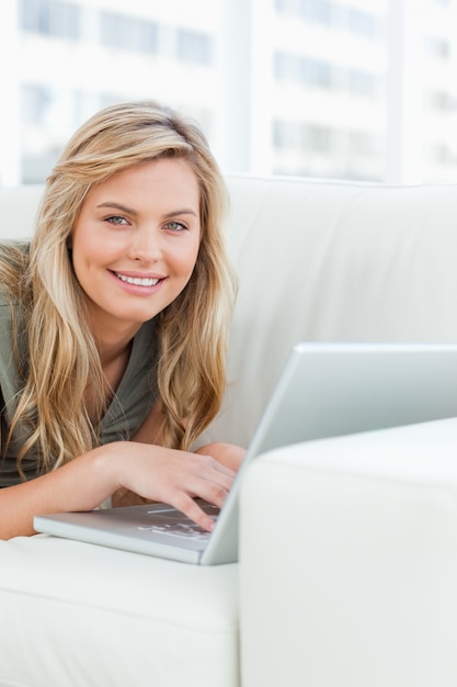 Photo close up, woman smiling as she looks forward, using her laptop