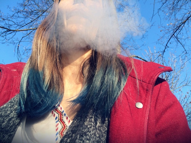 Foto close-up di una donna che fuma contro il cielo