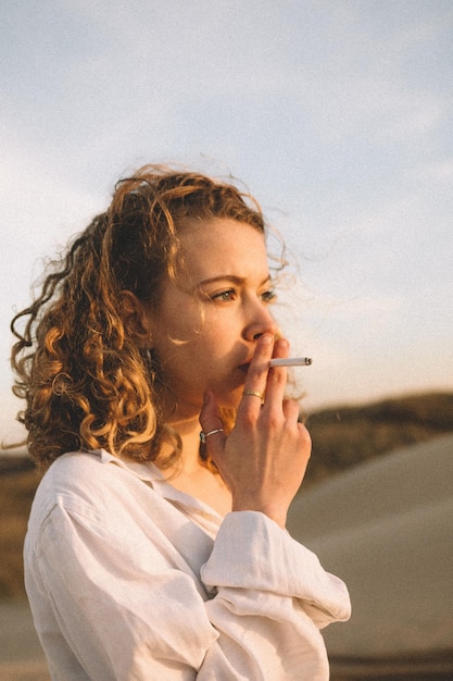 Photo close-up of woman smoking cigarette against sky