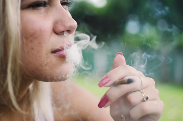 Foto close-up di una donna che fuma marijuana all'aperto