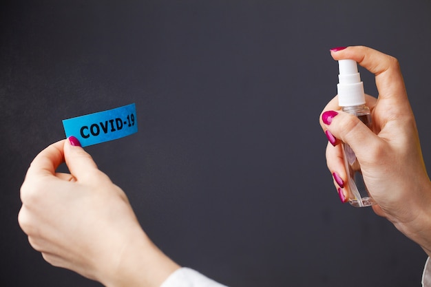 Close up of woman spraying antiseptic on coronavirus inscription