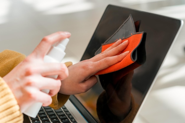 Chiudi la donna che spruzza lo spray sullo schermo del laptop