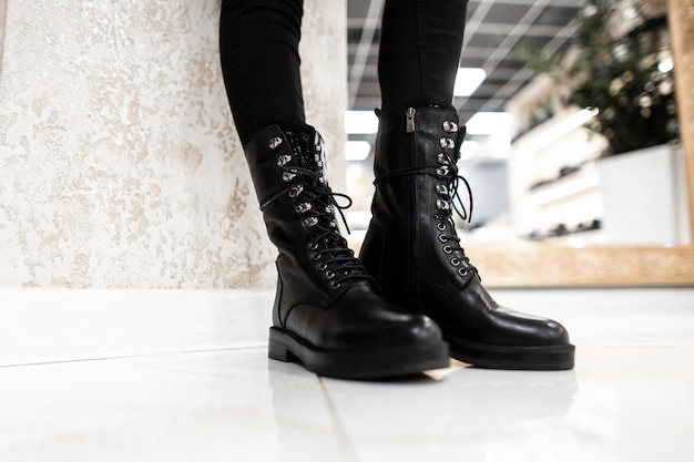 close up of woman standing on a tile in store in black cool leather lace-up boots