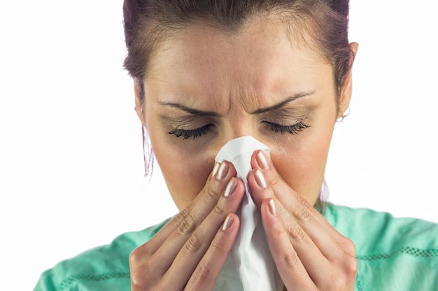 Close-up of woman suffering from cold with tissue on mouth 