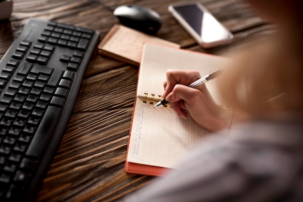 Close-up woman taking notes in agenda