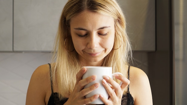 Close up of a woman taking in smell of coffee with her eyes closed 