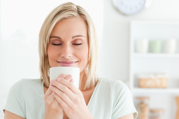 Close up of a woman taking in smell of coffee with her eyes closed