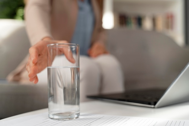 Foto terapista della donna del primo piano che raggiunge per il bicchiere d'acqua