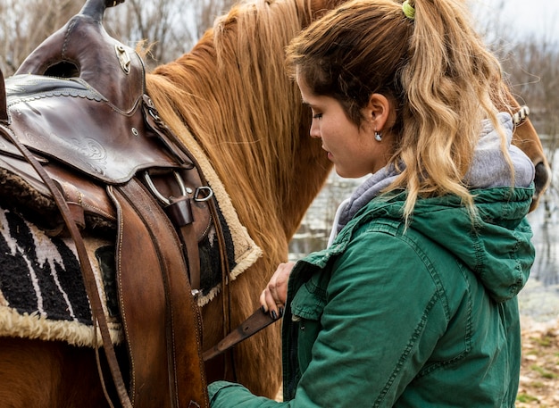 Close-up woman tying the saddle