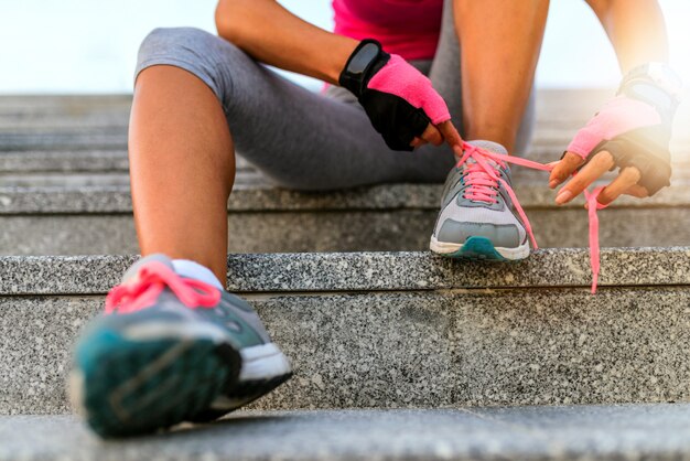 Close up of woman tying shoelaces outside during the day.