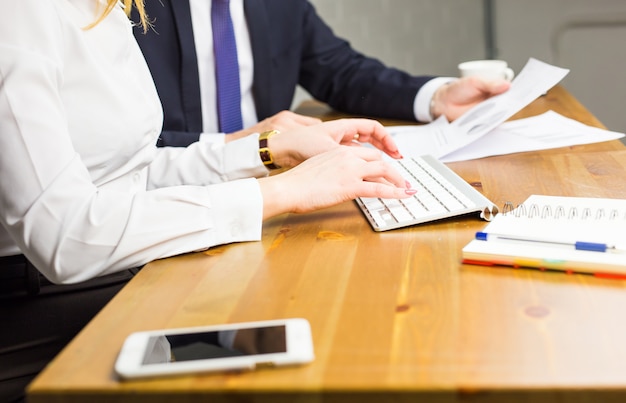 Primo piano della donna che digita sulla tastiera in ufficio.