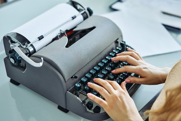 Foto chiuda in su della donna che scrive con la vecchia macchina da scrivere