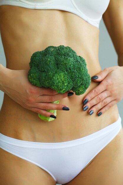 Close Up Of Woman In Underwear Holding Bunch Of Broccoli And Touching Stomach