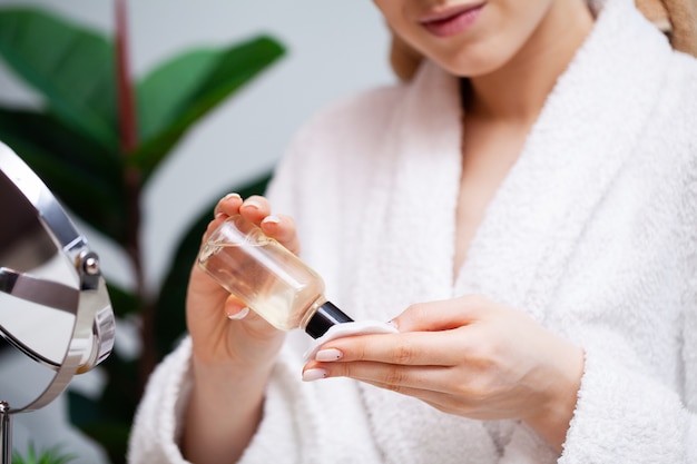 Close up woman uses liquid cream to care for face skin