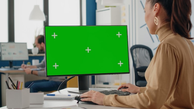 디스플레이에 격리된 녹색 화면이 있는 컴퓨터를 사용하는 여성의 클로즈업. 모니터에 모의 템플릿과 배경이 있는 크로마 키를 보고 있는 회사 직원. 빈 모형 복사 공간