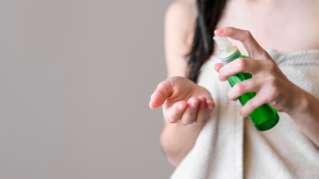 Foto donna del primo piano che per mezzo del prodotto per i capelli