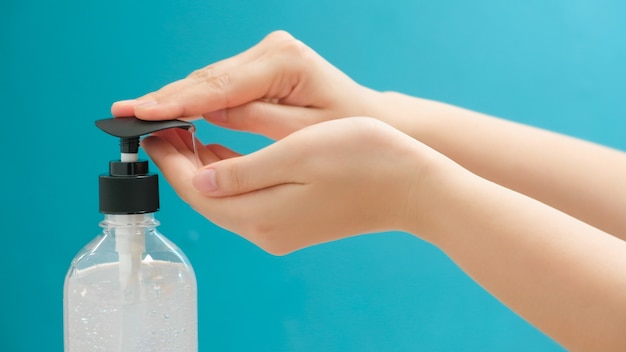 Chiuda su della donna che usando l'alcool del gel del prodotto disinfettante della mano