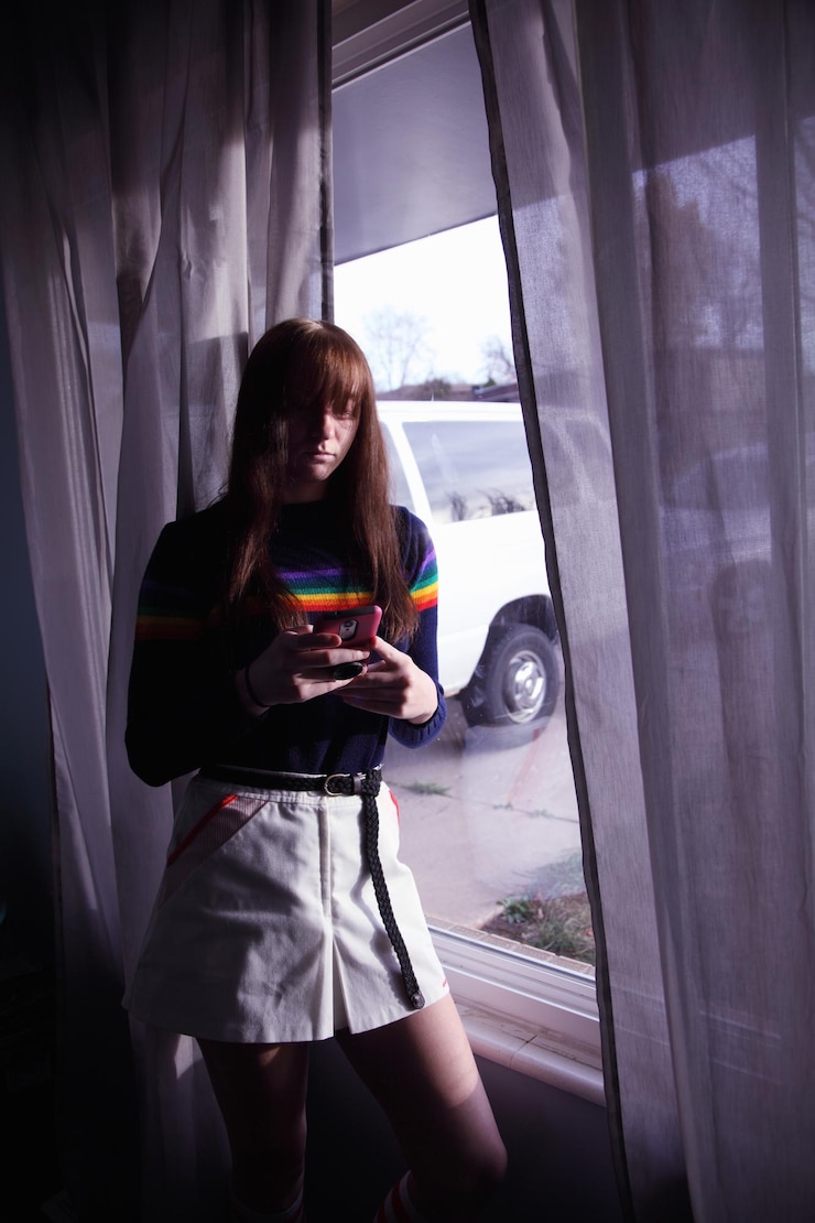 Photo 窓のそばで携帯電話を使っている女性のクローズアップ