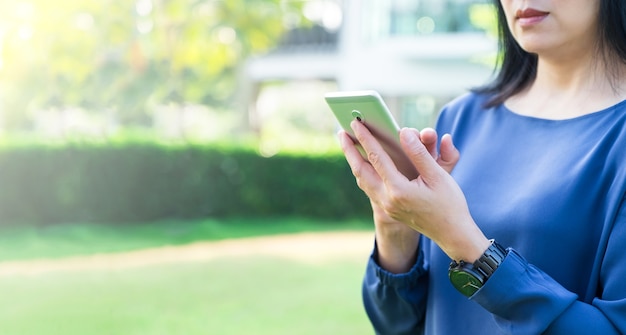 緑の庭で家の外で携帯電話を使用して女性を閉じます