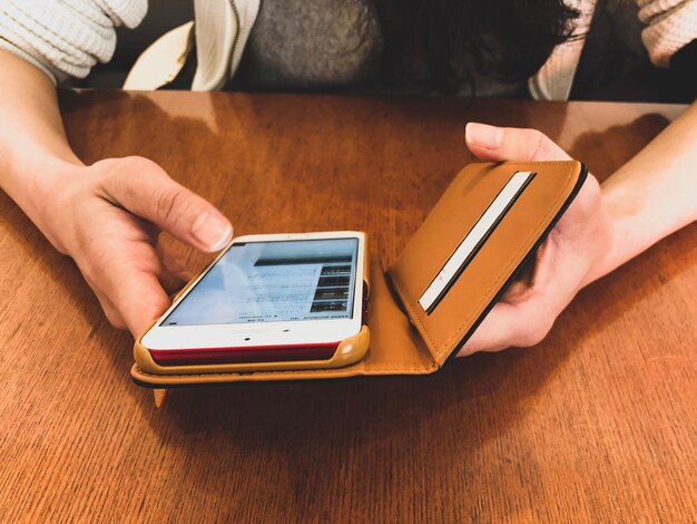 Photo close-up of woman using mobile phone on table at home