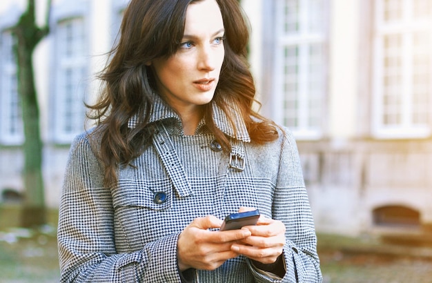 Photo close-up of woman using smart phone while standing against building