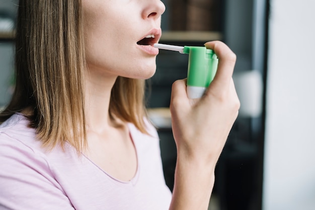 Primo piano di una donna usando spray per la gola