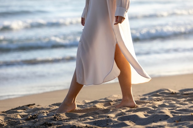 Chiuda sulla donna che cammina sulla spiaggia