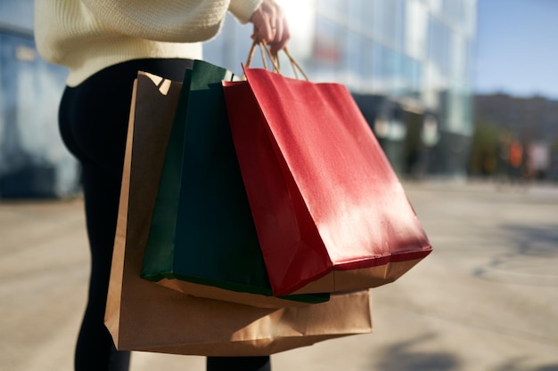 Foto chiuda in su della donna che cammina con le borse della spesa in mano in città dal centro commerciale inquadratura dal basso della ragazza che va