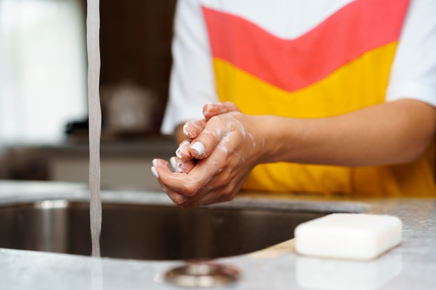Foto chiuda in su di una donna che si lava le mani in un lavandino della cucina