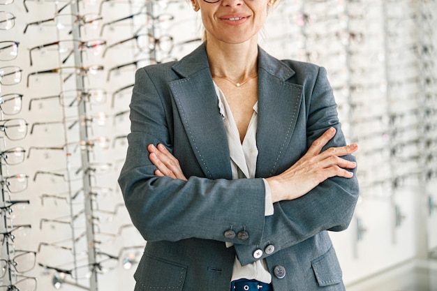 Close up of woman wearing jacket standing on a background of showcases with glasses