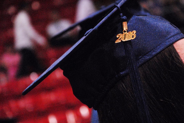 Foto close-up di una donna che indossa mortarboard con il numero 2016